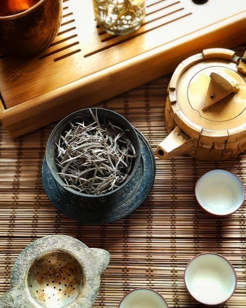 Silver needle white tea buds unfurling in a glass teapot